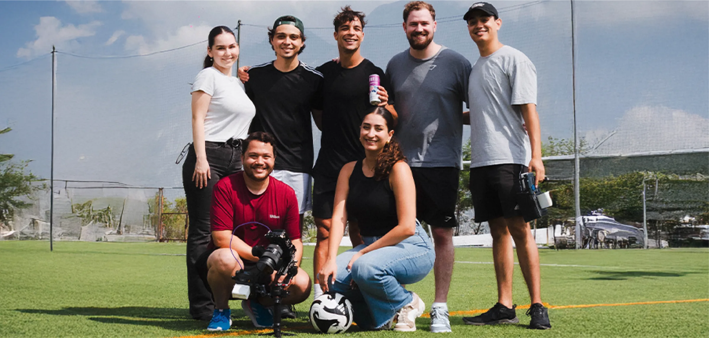 A group on the football pitch after the shoot, holding Freelife cans.